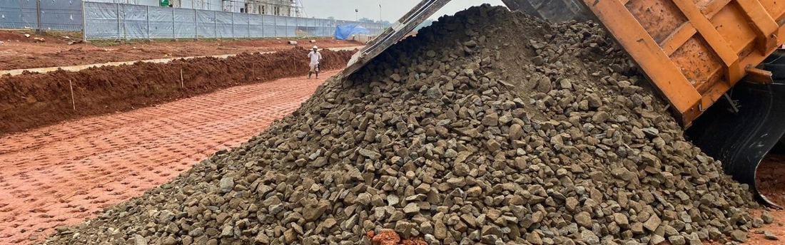 Pengiriman dan penghamparan material agregat di lokasi proyek